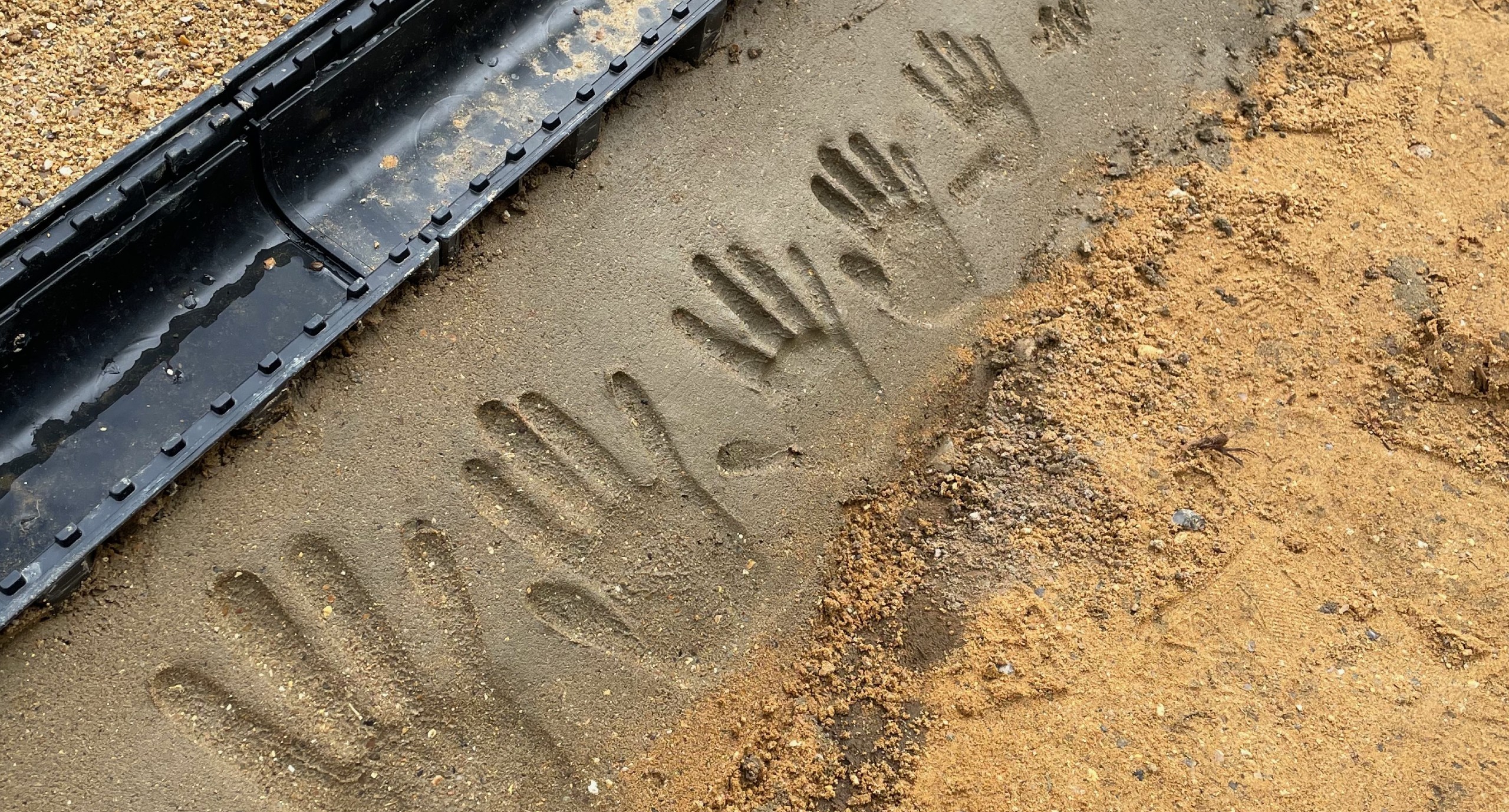Handprints in fresh concrete during a family home renovation project in Surrey