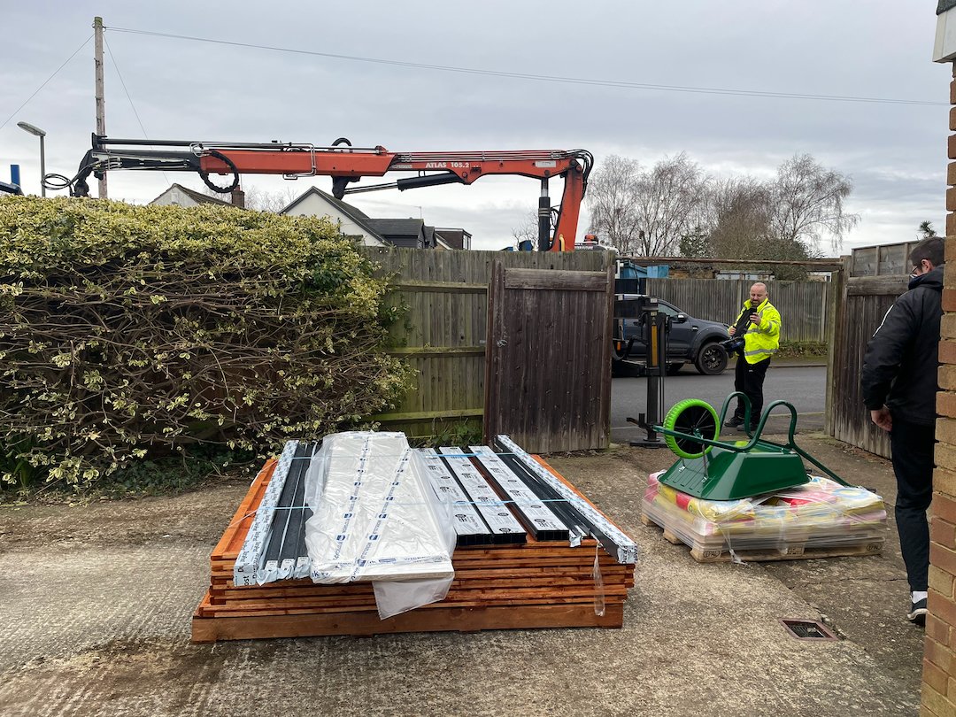 Fence panels, steel posts and building materials delivered for a garden boundary renovation project in Surrey.