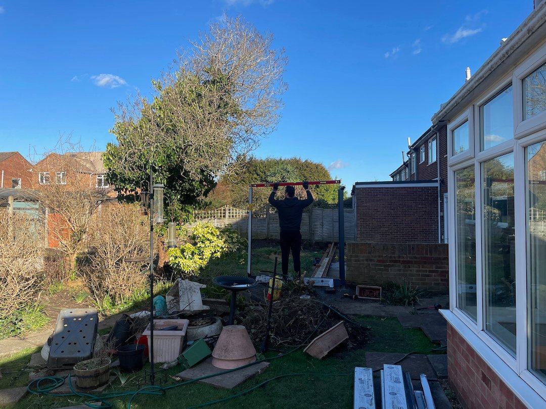Checking levels and positioning steel fence posts during a garden fence installation in Surrey.