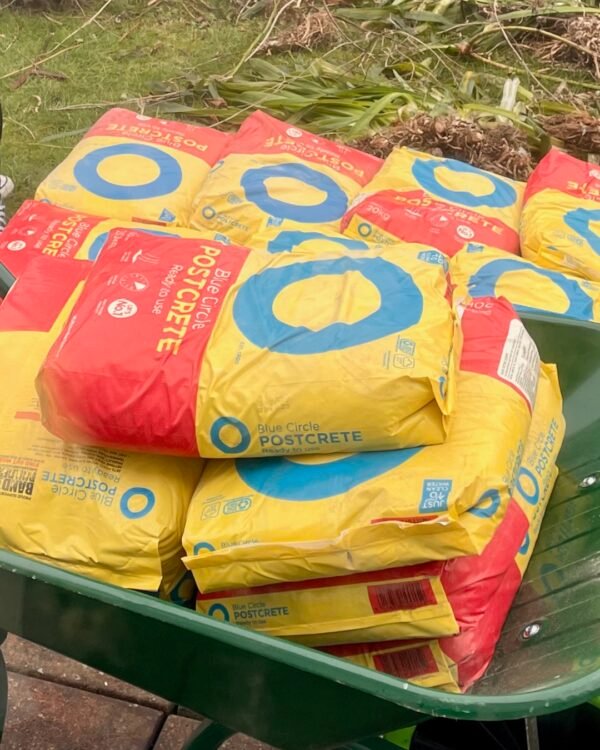 Blue Circle Postcrete 20kg bags piled in a wheelbarrow for a garden renovation project by Renovating Life UK.