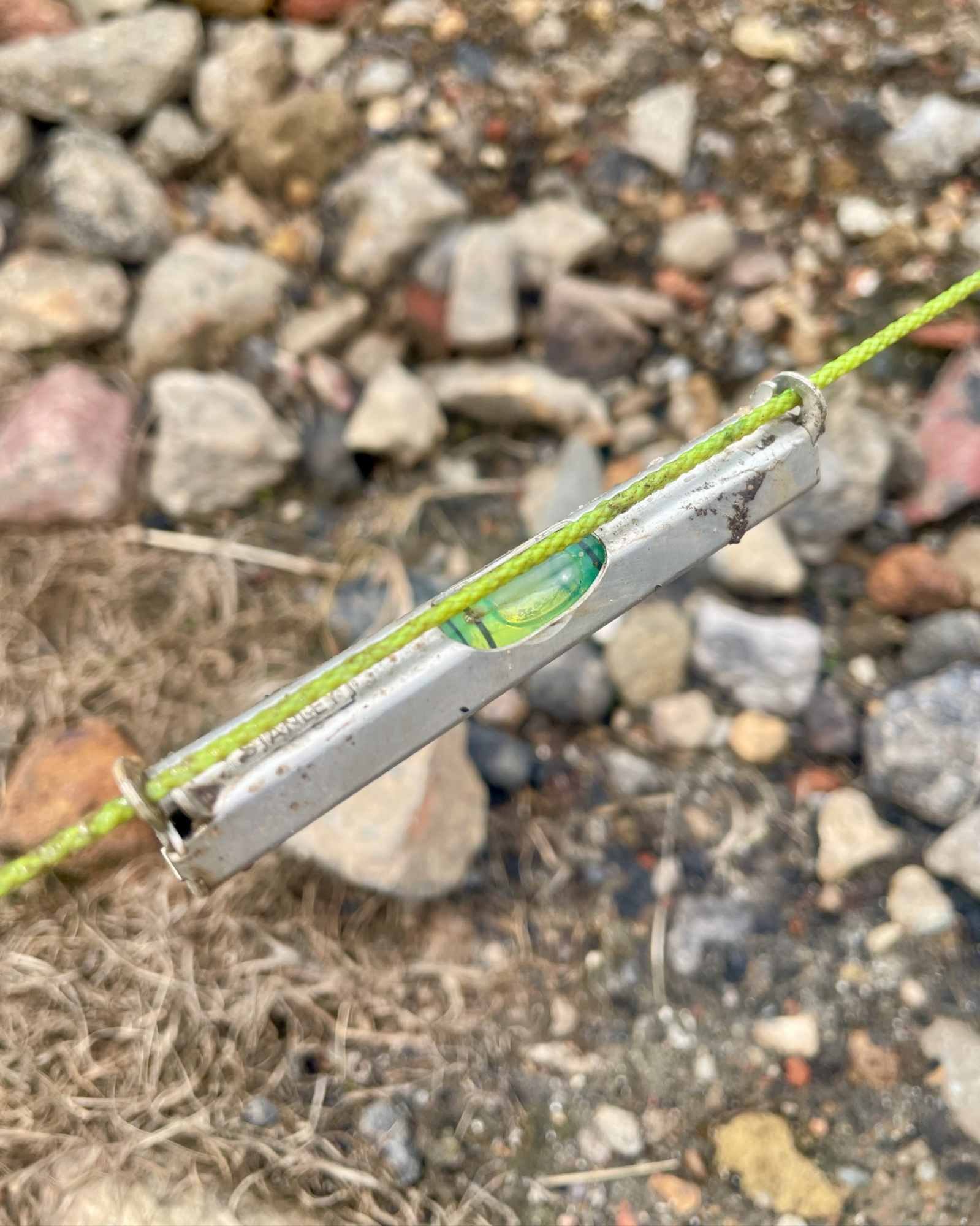 Classic Stanley 80mm metal line spirit level hooked onto a brick line for garden landscaping.