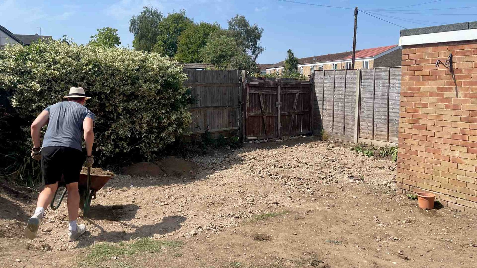 Wheelbarrow removing rubble and crushed concrete while preparing the garden for a new lawn in Surrey.